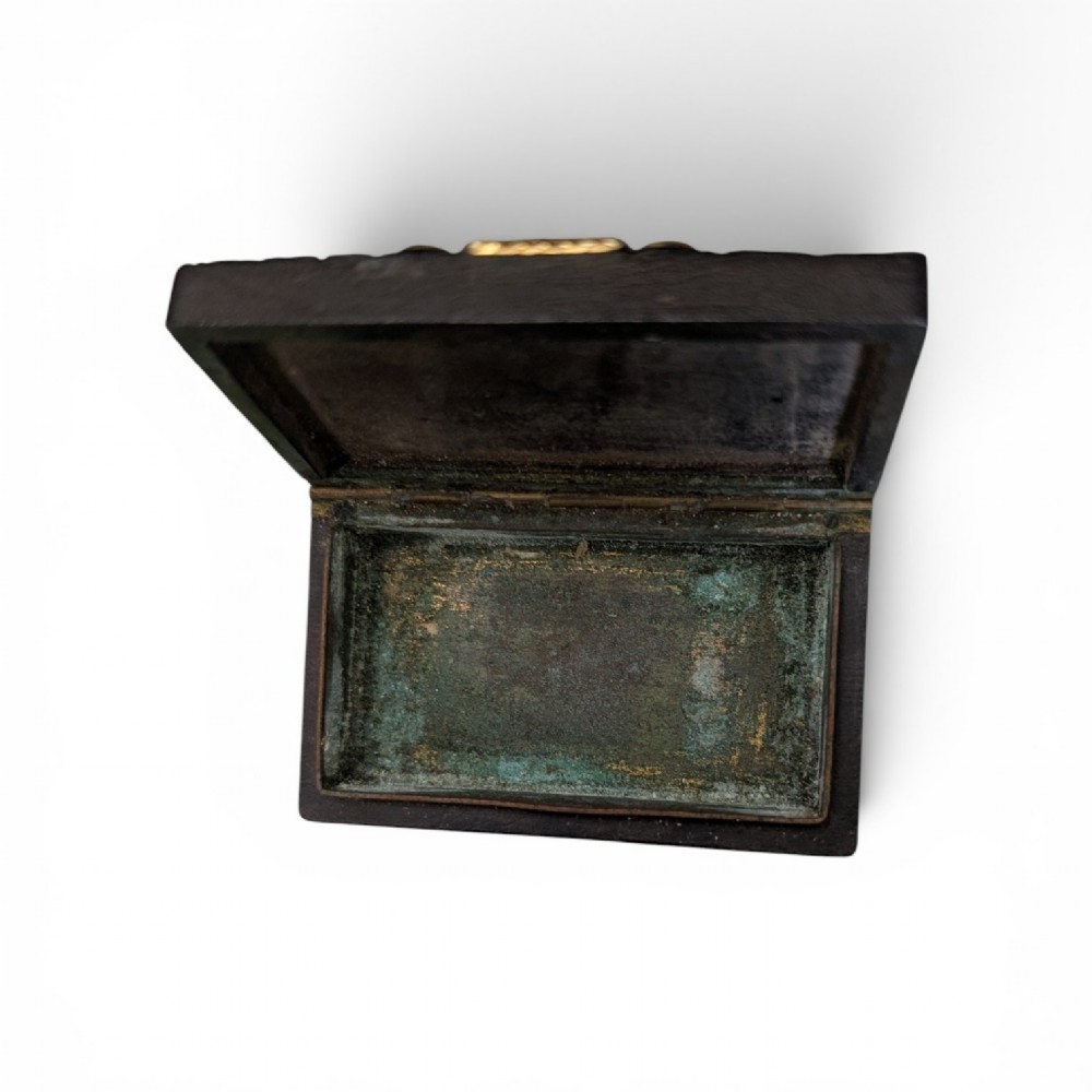 A rectangular 19th-century dark brown rhinoceros hide snuff box featuring an ornate gilt metal central cartouche and matching clasp. View VII