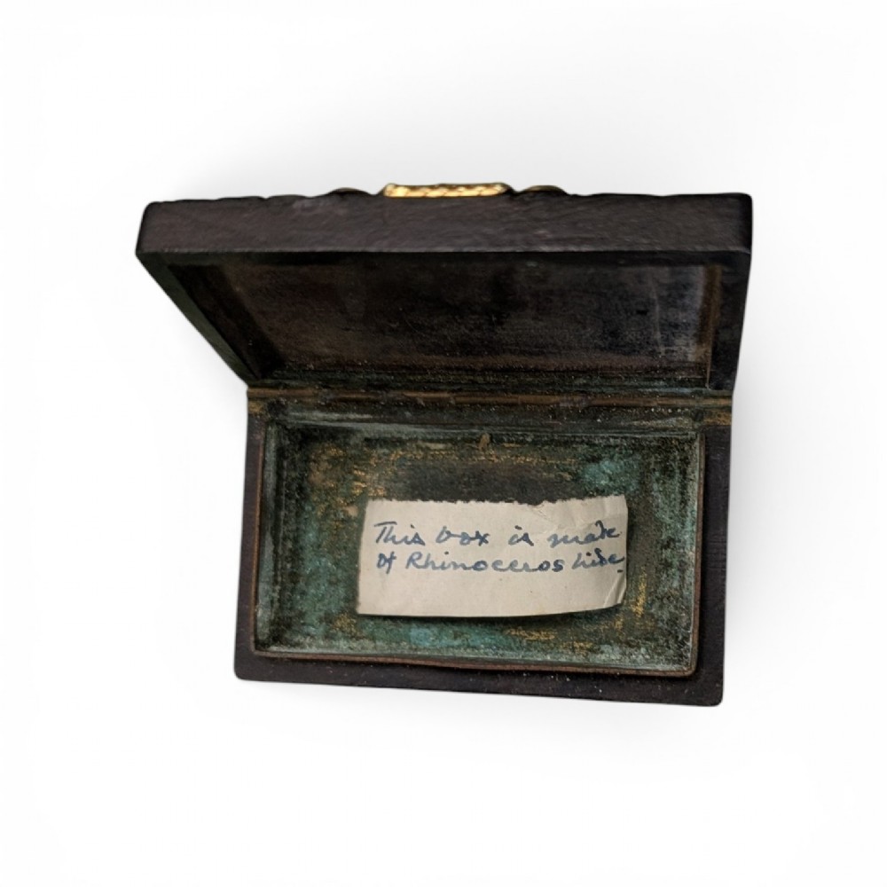 A rectangular 19th-century dark brown rhinoceros hide snuff box featuring an ornate gilt metal central cartouche and matching clasp. View VIII
