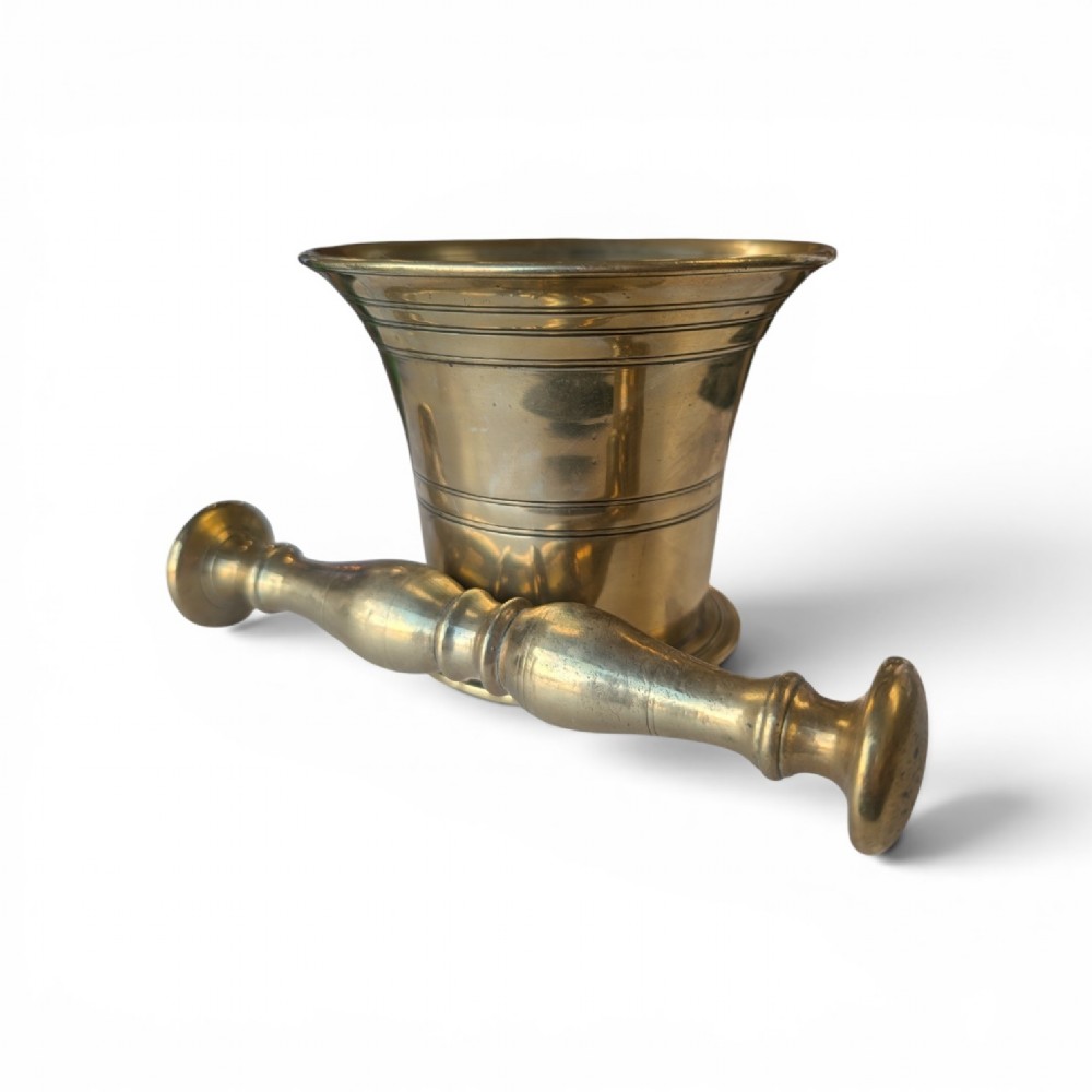 A cast brass mortar with a flared upper rim and incised lines, shown alongside a turned brass pestle. View III