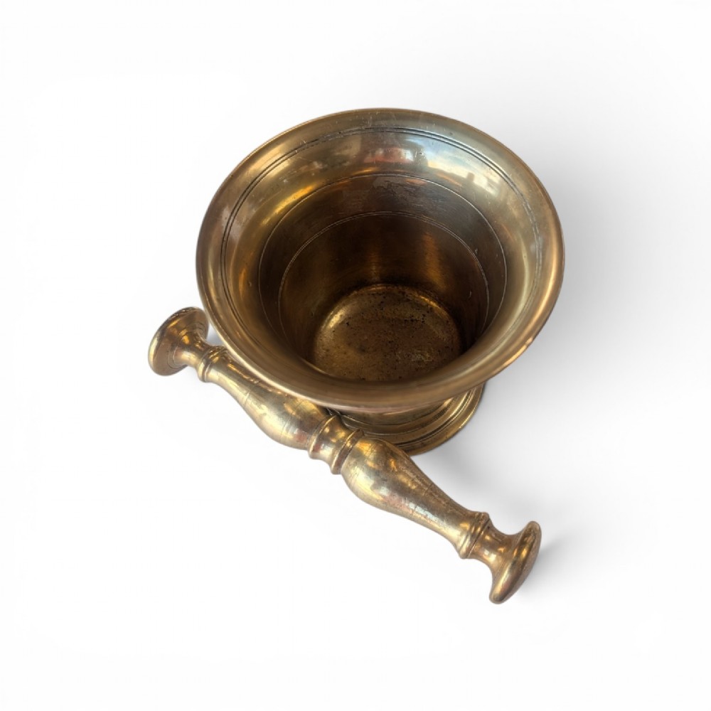 A cast brass mortar with a flared upper rim and incised lines, shown alongside a turned brass pestle. View IV