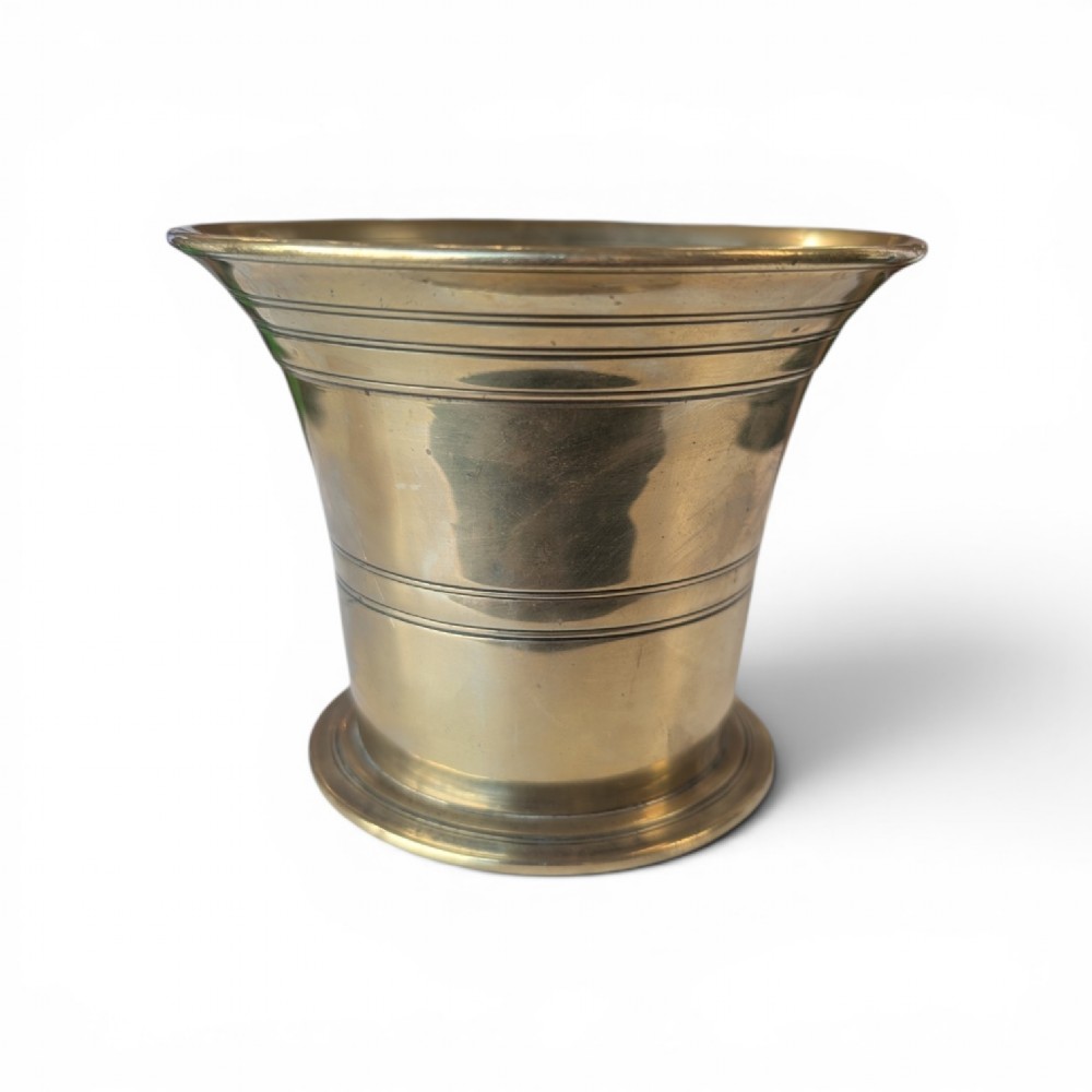 A cast brass mortar with a flared upper rim and incised lines, shown alongside a turned brass pestle. View VI