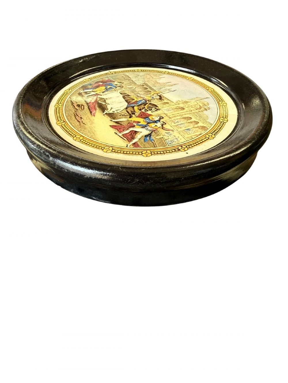 A circular ceramic plate depicting a transfer-printed bullfighting scene, framed within a wide circular black ebonised surround. View II