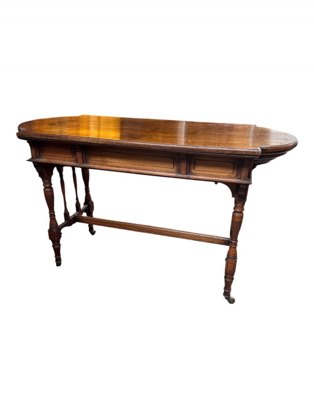 An antique warm brown oak library table featuring turned fluted legs, vertical spindle stretchers, and a polished rectangular top with rounded edges.