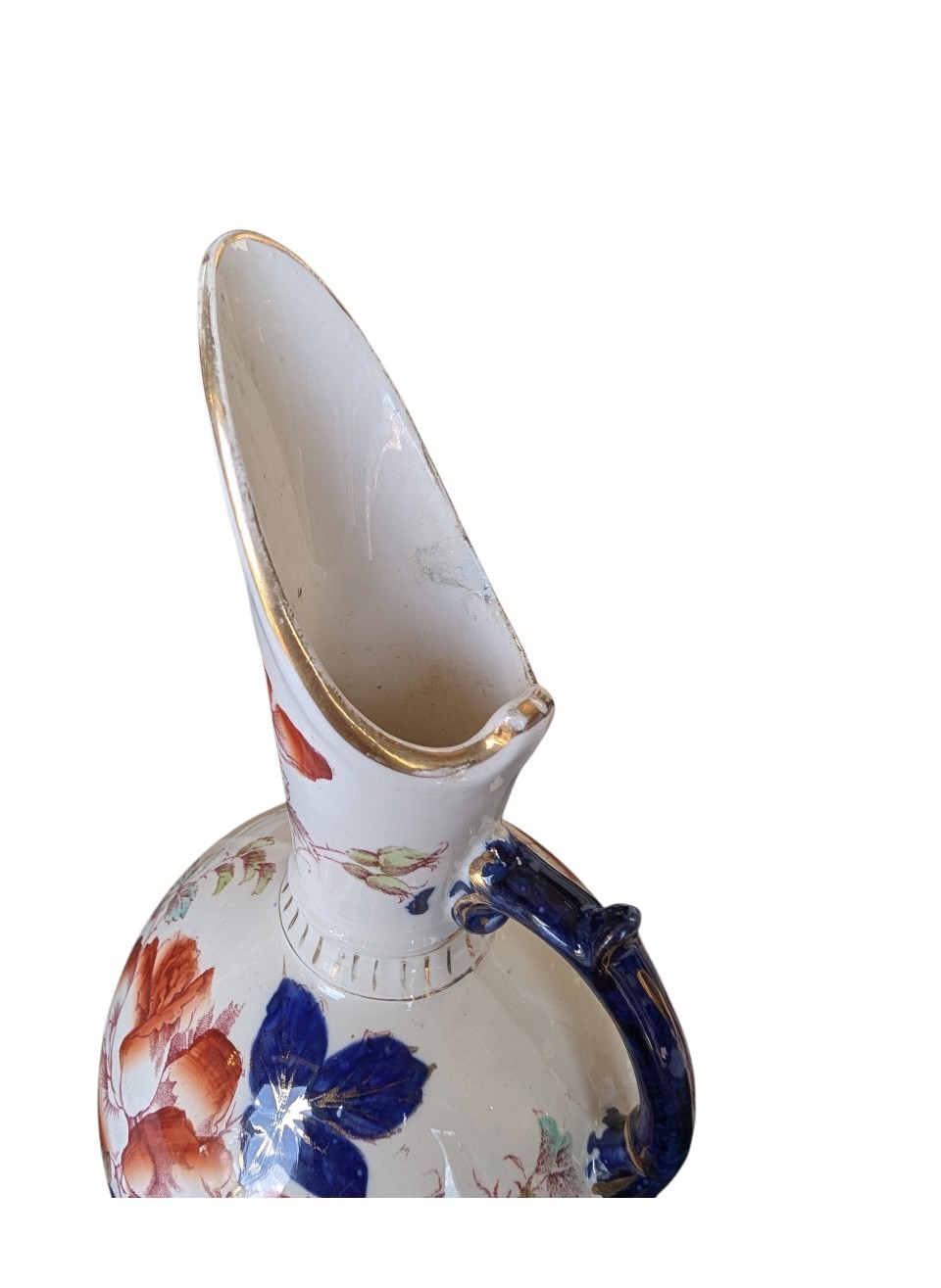 A pair of antique Japanese Imari porcelain pitchers featuring rounded bodies, tall swept spouts, dark blue handles, and hand-painted rust red flowers with gilded accents. View V