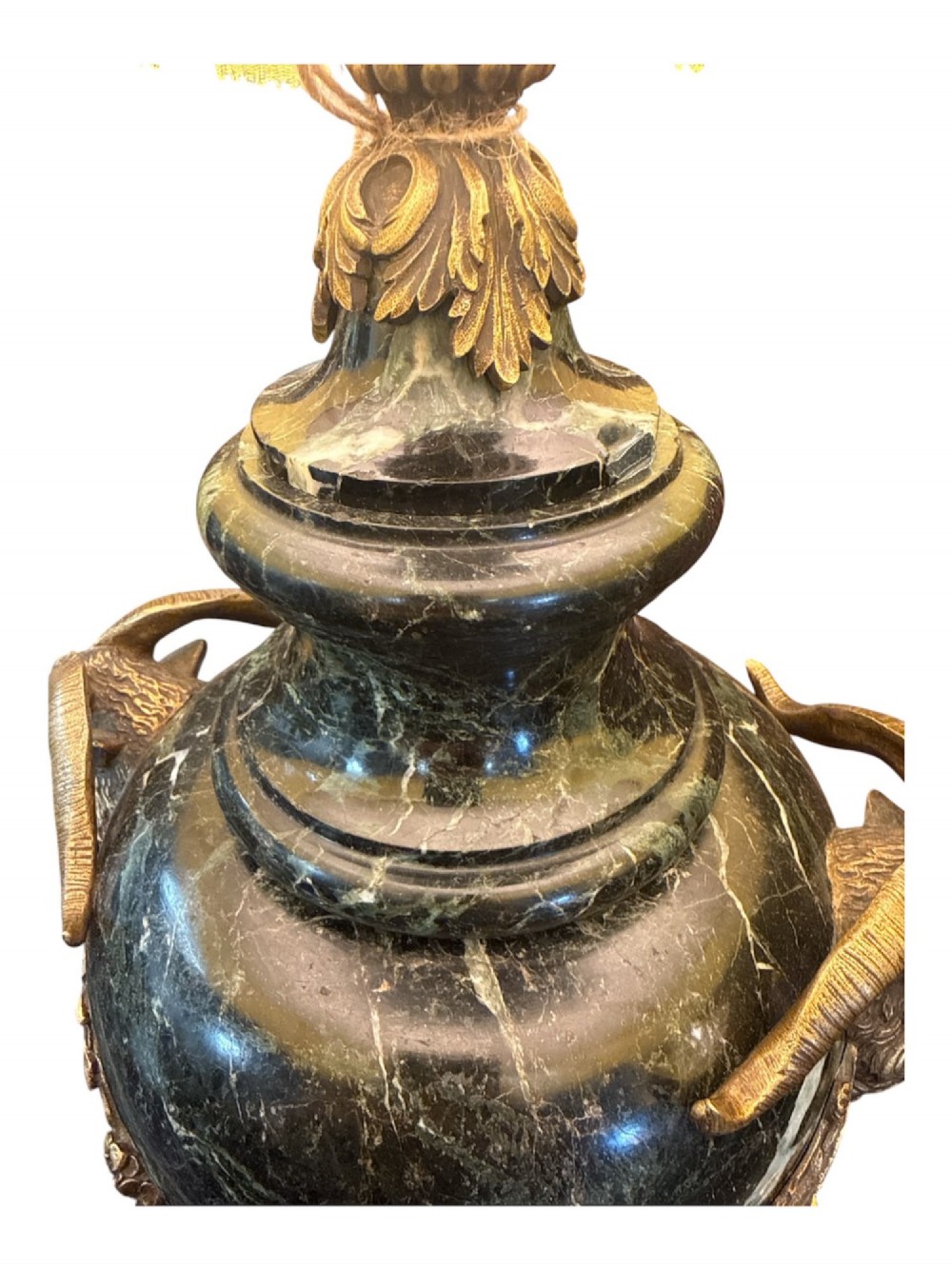A pair of 19th-century French table lamps crafted from dark veined marble in urn shapes with gilt metal mounts and amber fabric shades featuring fringe trim. View II