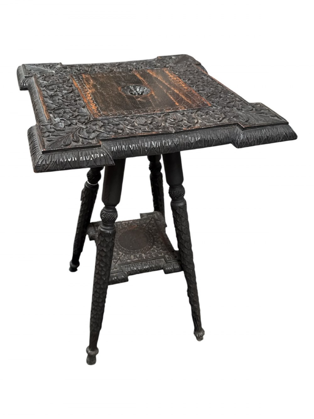 A 19th-century dark hardwood Anglo-Indian occasional table featuring intricately carved scale motifs on the legs, a carved undertier shelf, and a textured top. View III