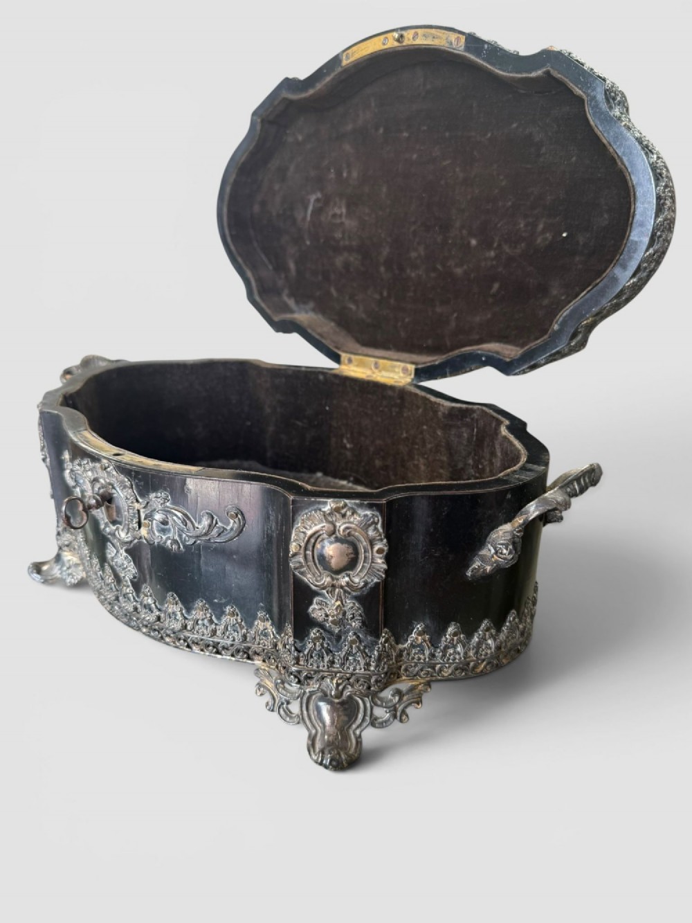 A 19th-century French ebonised serpentine table casket featuring elaborate silvered metal scrollwork mounts, raised feet, and a lid top decorated with a winged bird finial. View VIII