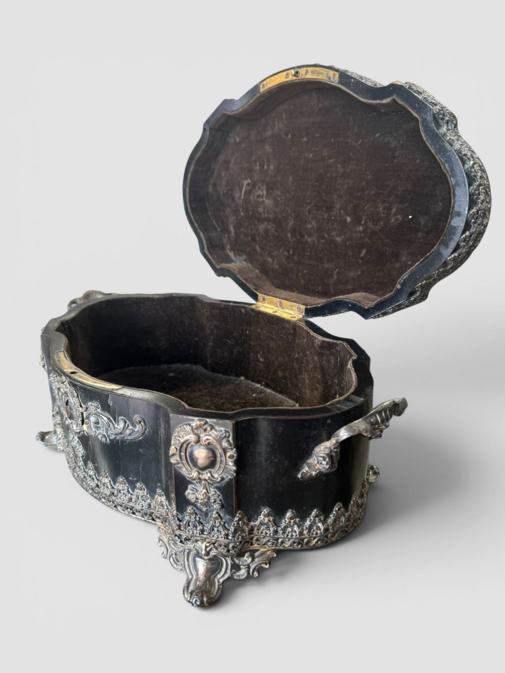A 19th-century French ebonised serpentine table casket featuring elaborate silvered metal scrollwork mounts, raised feet, and a lid top decorated with a winged bird finial. View X