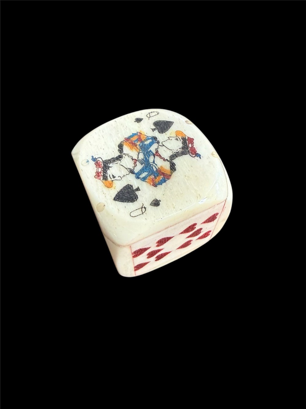 A cream-coloured carved bone poker die decorated with hand-coloured playing card suits and figures on each face. View II