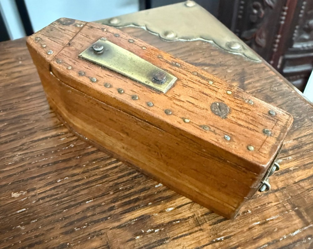 A coffin-shaped wooden puzzle snuff box decorated with a central brass plate and metal studs. View II