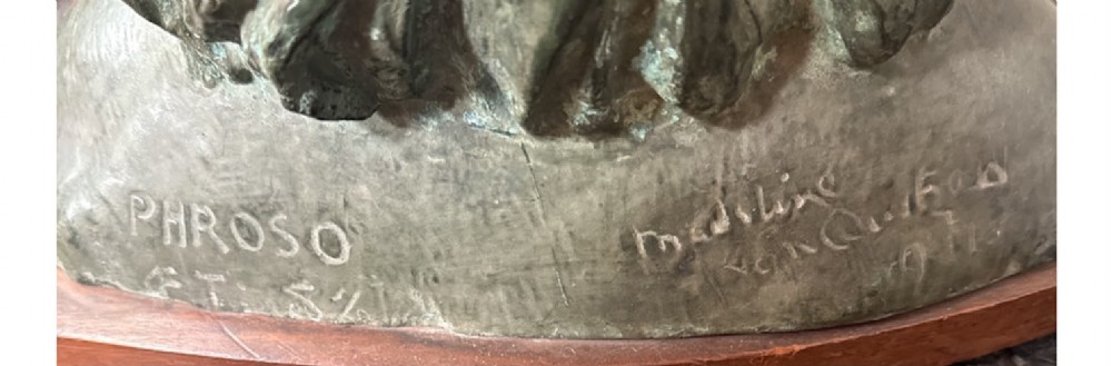 A bronzed metal portrait bust of a young girl with shoulder-length hair, mounted on a curved wooden base. View III