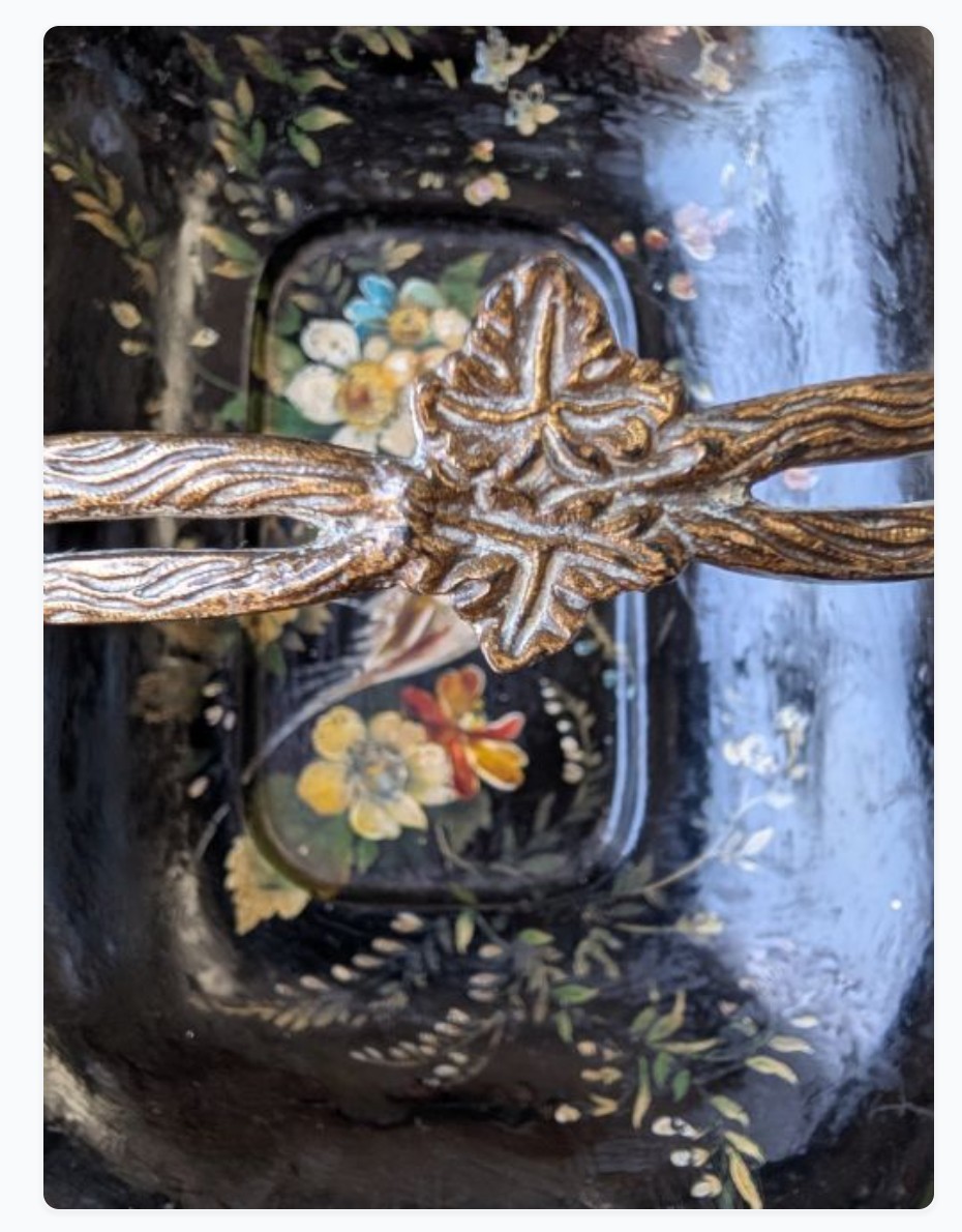 Victorian black lacquered papier-mache basket featuring hand-painted floral motifs, a bird illustration, a scalloped border, and a gilt metal swing handle. View IX