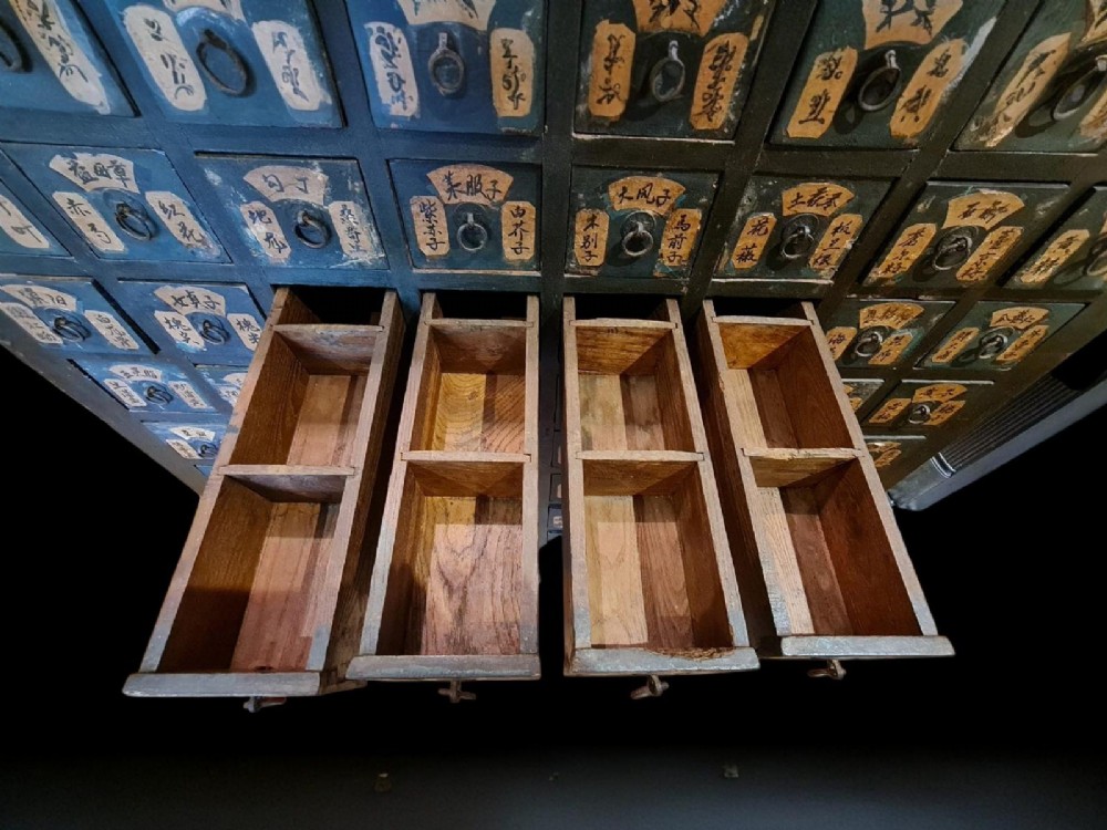 A tall dark elm Chinese apothecary chest featuring multiple small drawers inscribed with calligraphic characters above three larger base drawers. View IX