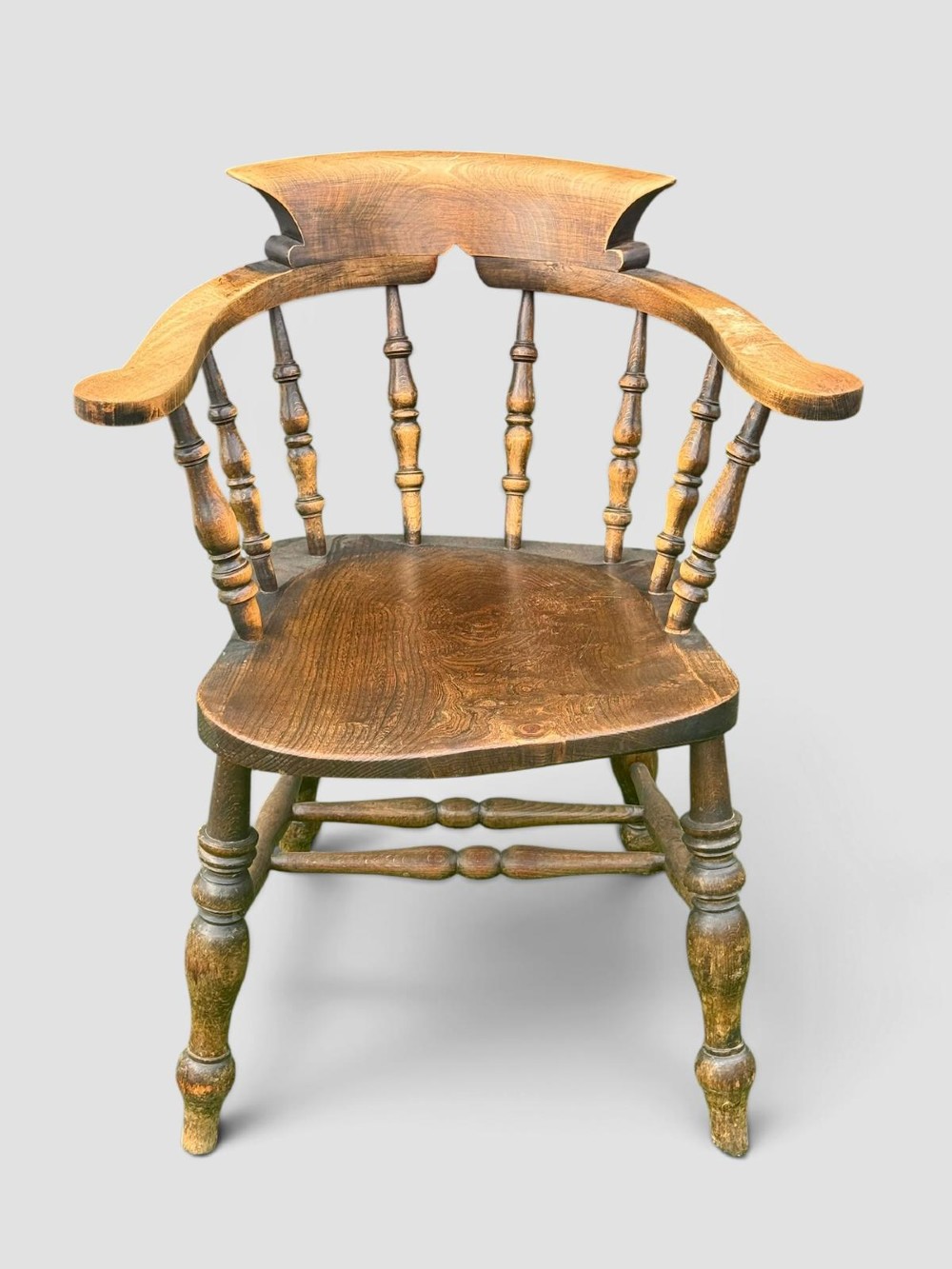 An antique Victorian beech and elm smokers captains chair with turned spindles, a contoured saddle seat, and turned legs. View IV