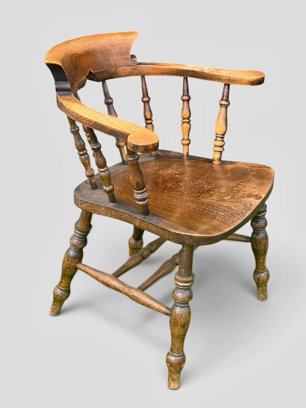 An antique Victorian beech and elm smokers captains chair with turned spindles, a contoured saddle seat, and turned legs. View VII