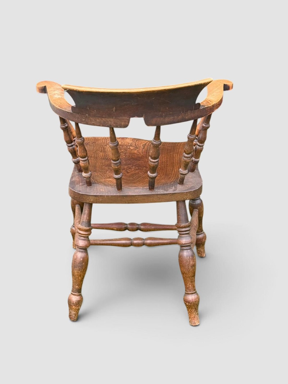 An antique Victorian beech and elm smokers captains chair with turned spindles, a contoured saddle seat, and turned legs. View VIII