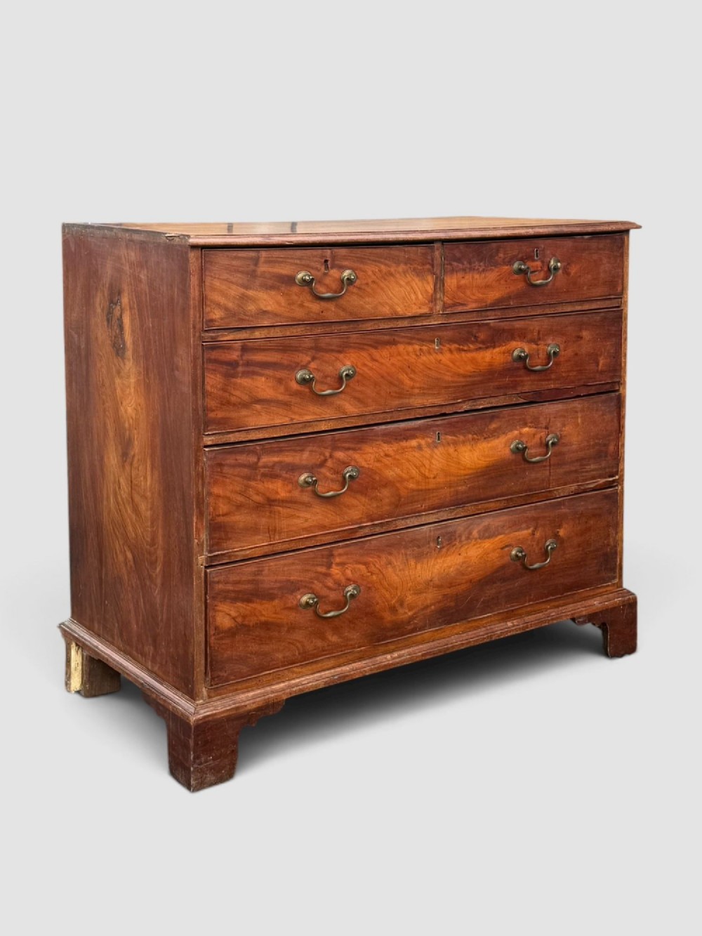 A Georgian mahogany chest of drawers featuring a two-over-three drawer configuration with brass swan-neck handles and bracket feet. View II