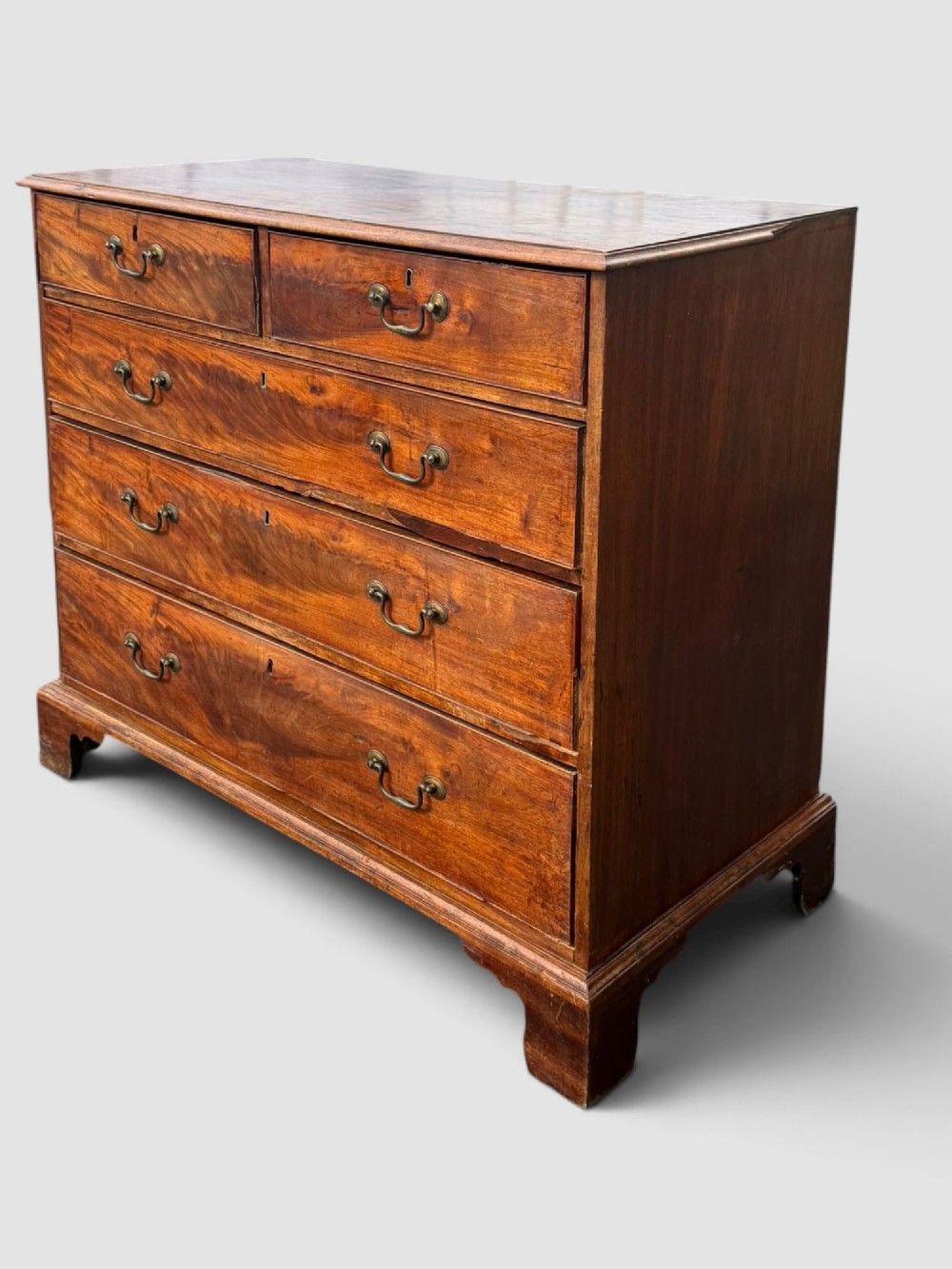 A Georgian mahogany chest of drawers featuring a two-over-three drawer configuration with brass swan-neck handles and bracket feet. View VII