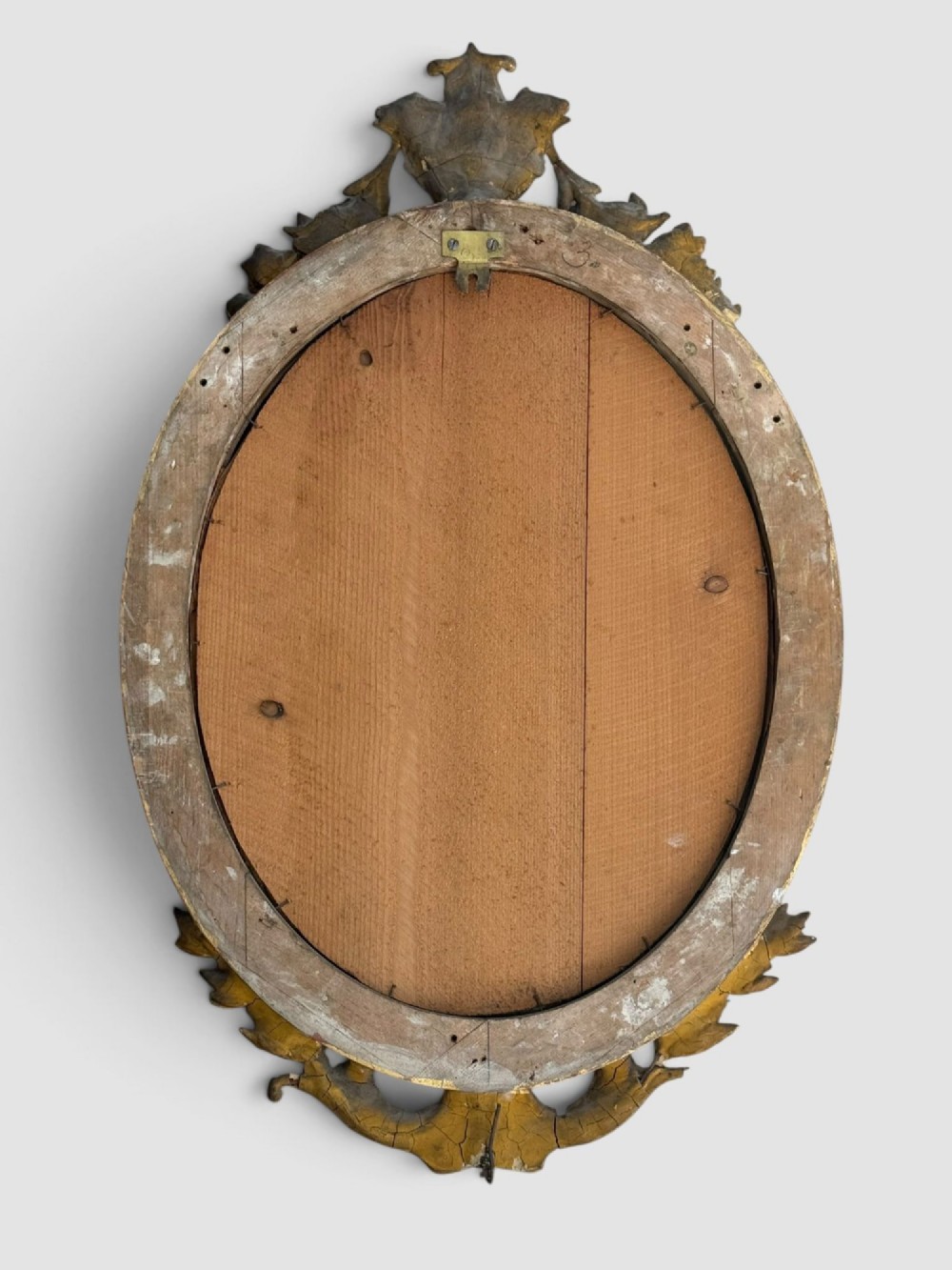 An oval Victorian gilt gesso wall mirror featuring an ornate floral crest, decorative scrollwork, and bevelled mirror glass. View VIII