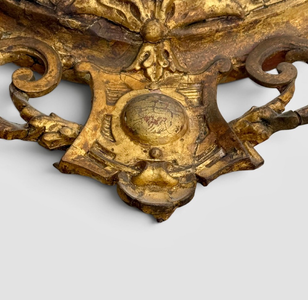 An oval Victorian giltwood and gesso girandole wall mirror featuring floral cresting, a beaded inner rim, and a three-branch candle sconce at the base. View VII
