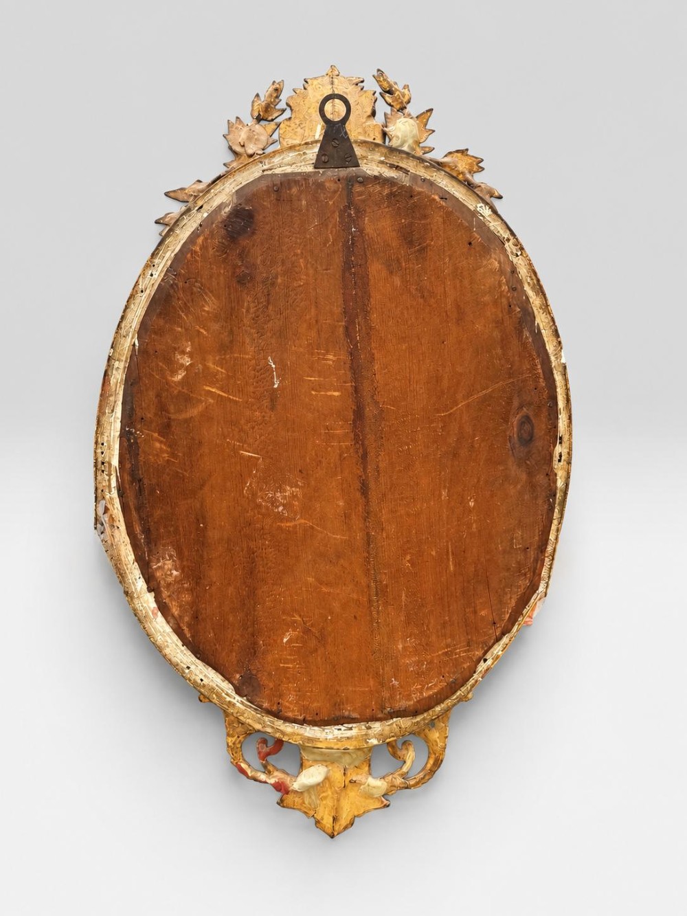 An oval Victorian giltwood and gesso girandole wall mirror featuring floral cresting, a beaded inner rim, and a three-branch candle sconce at the base. View X