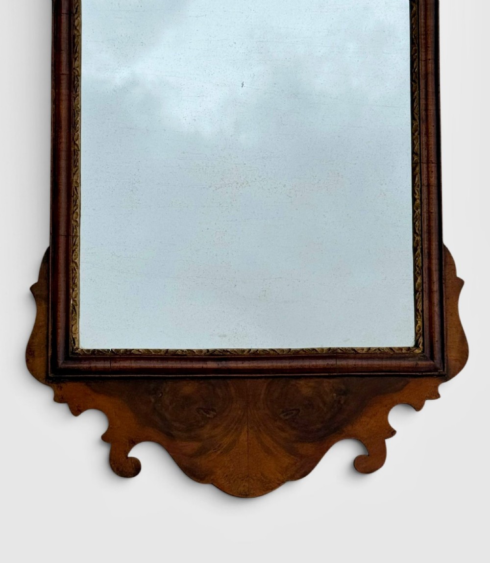 An 18th-century Georgian wall mirror featuring a carved walnut fretwork frame with a central gilded plume motif at the top. View II