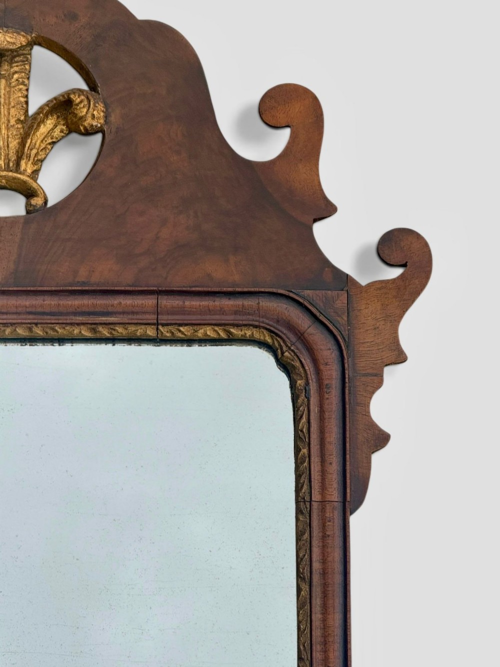 An 18th-century Georgian wall mirror featuring a carved walnut fretwork frame with a central gilded plume motif at the top. View X