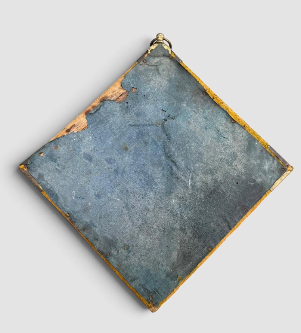 A diamond-shaped wall mirror featuring a mustard yellow velvet frame with decorative brass corner mounts, a central round bevelled glass mirror, and an integrated brass candle sconce at the lower vertex. View VII