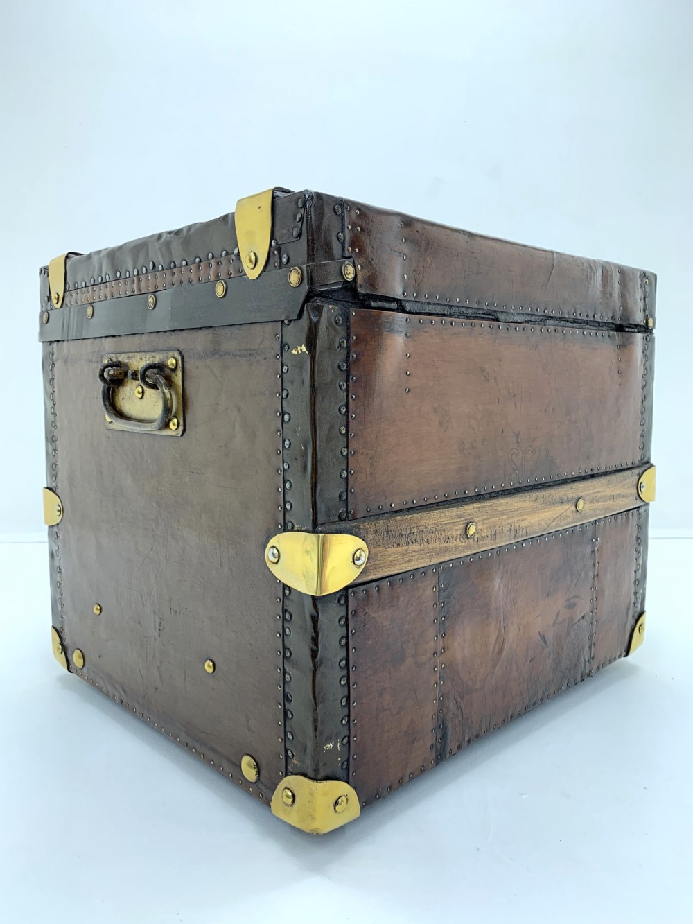 A dark brown antique leather steamer trunk featuring brass hardware, riveted metal stud trim, and wooden reinforcement bands. View III