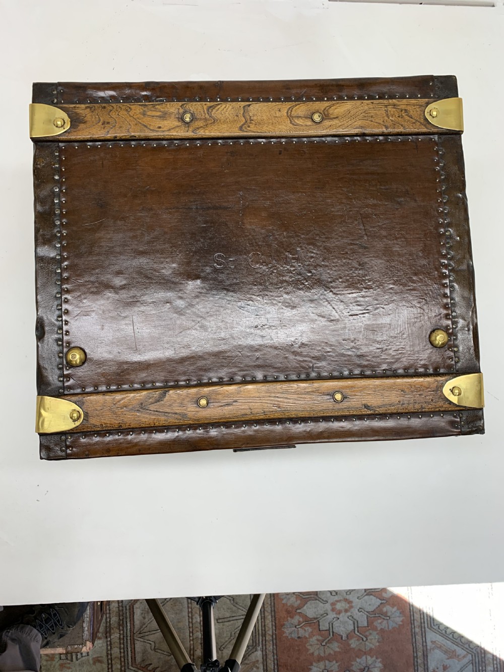 A dark brown antique leather steamer trunk featuring brass hardware, riveted metal stud trim, and wooden reinforcement bands. View VI