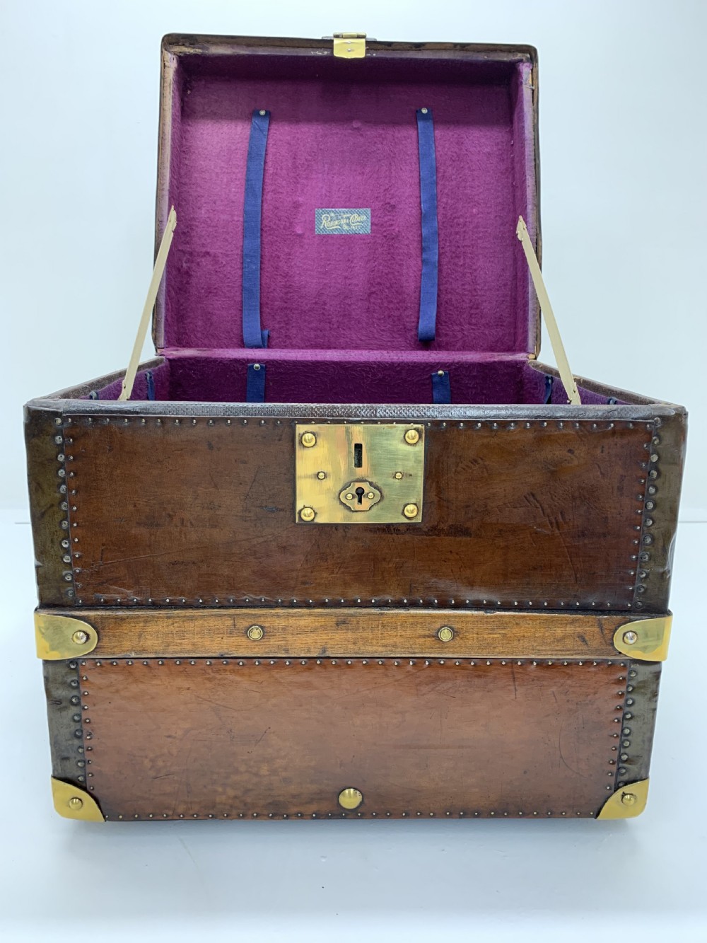 A dark brown antique leather steamer trunk featuring brass hardware, riveted metal stud trim, and wooden reinforcement bands. View VIII