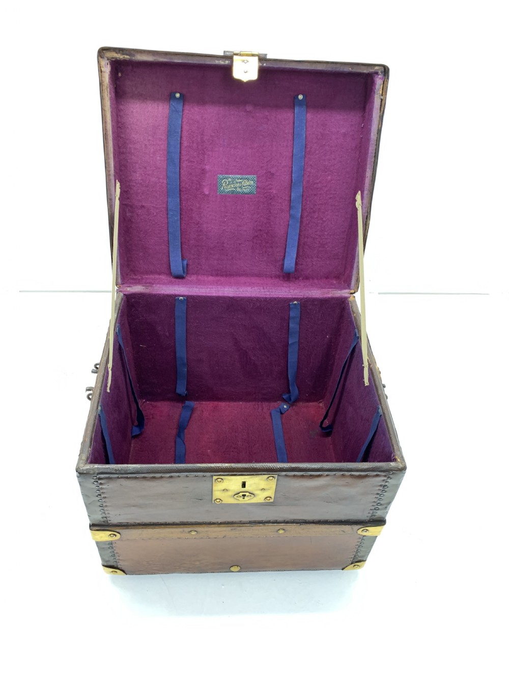 A dark brown antique leather steamer trunk featuring brass hardware, riveted metal stud trim, and wooden reinforcement bands. View IX
