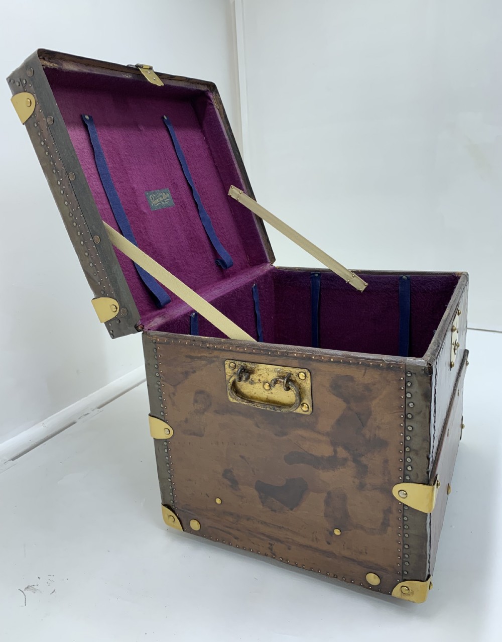 A dark brown antique leather steamer trunk featuring brass hardware, riveted metal stud trim, and wooden reinforcement bands. View XV