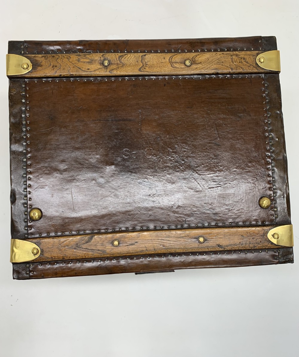A dark brown antique leather steamer trunk featuring brass hardware, riveted metal stud trim, and wooden reinforcement bands. View XVI
