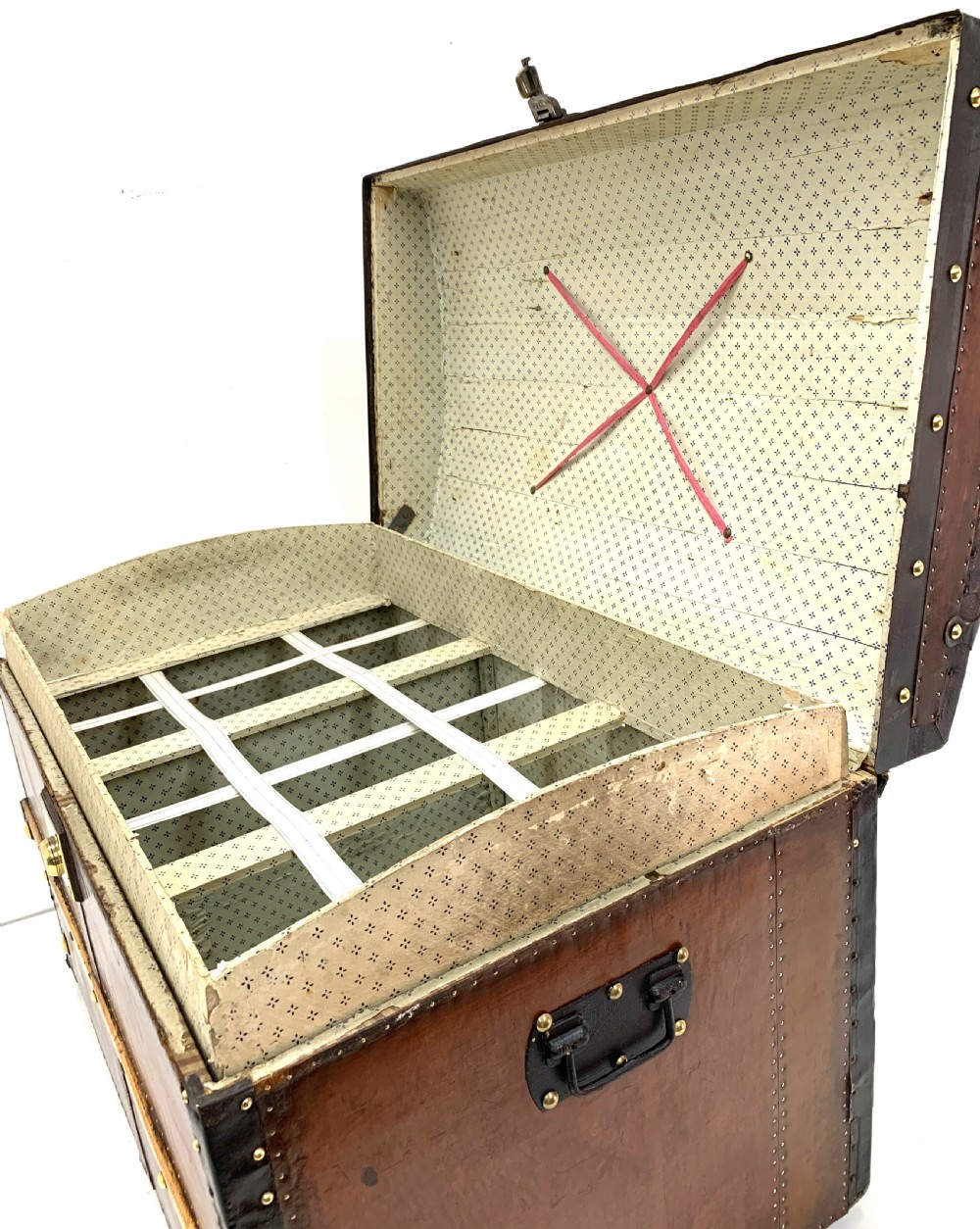 An antique leather-bound dome top steamer trunk with brass studs, wooden slats, and a central brass lock mechanism. View XV