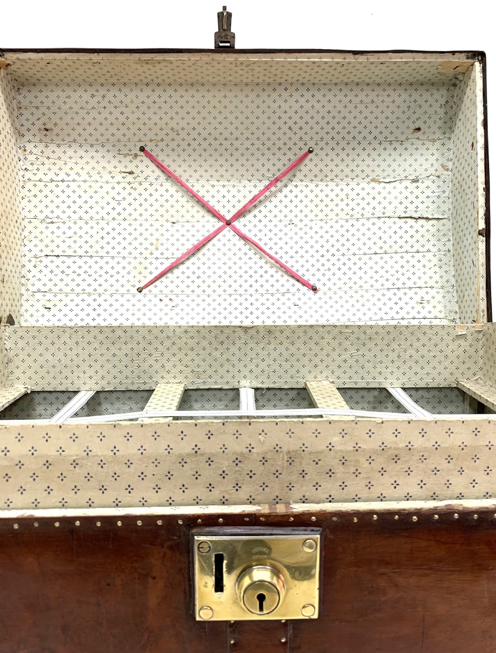 An antique leather-bound dome top steamer trunk with brass studs, wooden slats, and a central brass lock mechanism. View XVI