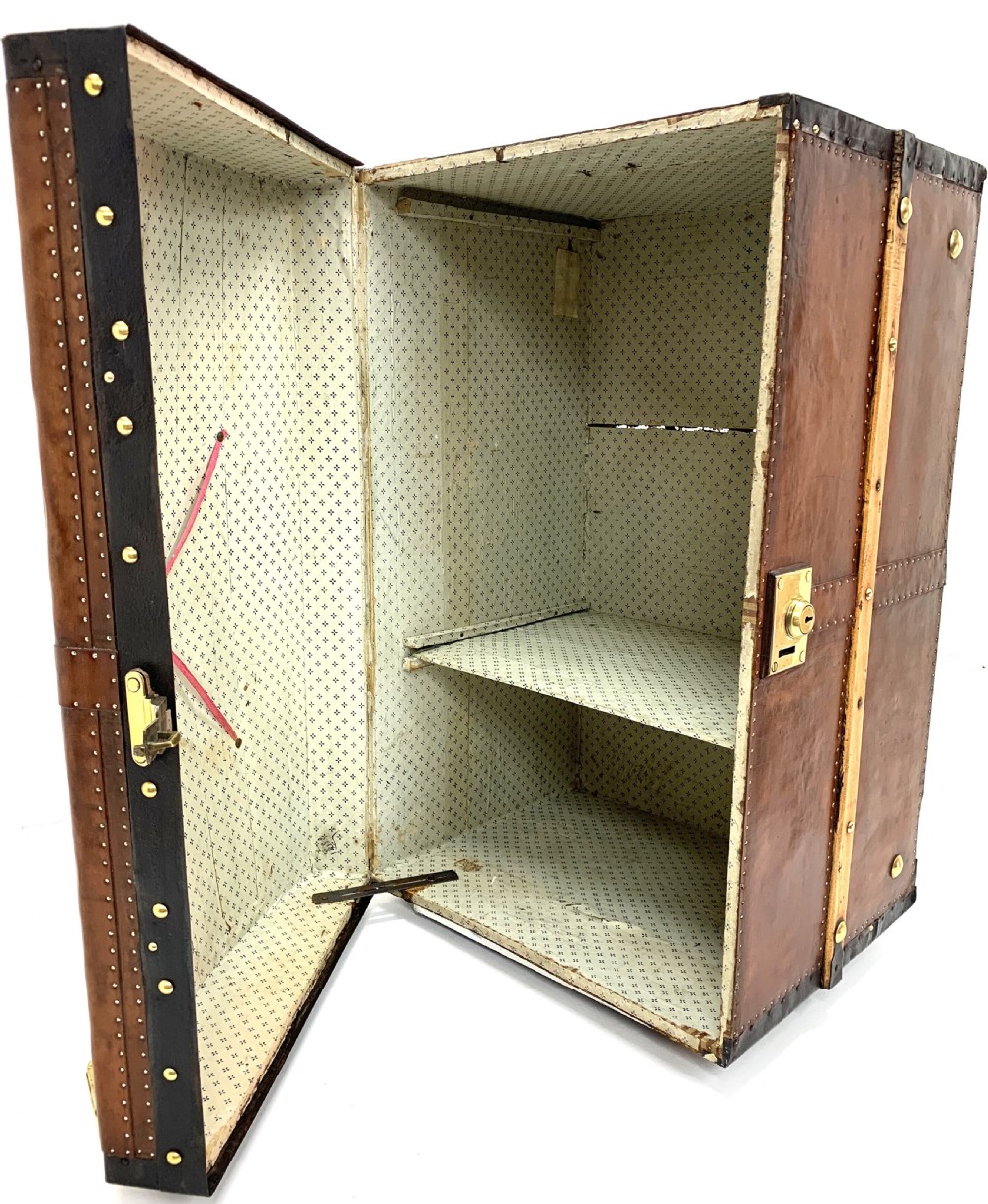 An antique leather-bound dome top steamer trunk with brass studs, wooden slats, and a central brass lock mechanism. View XVIII