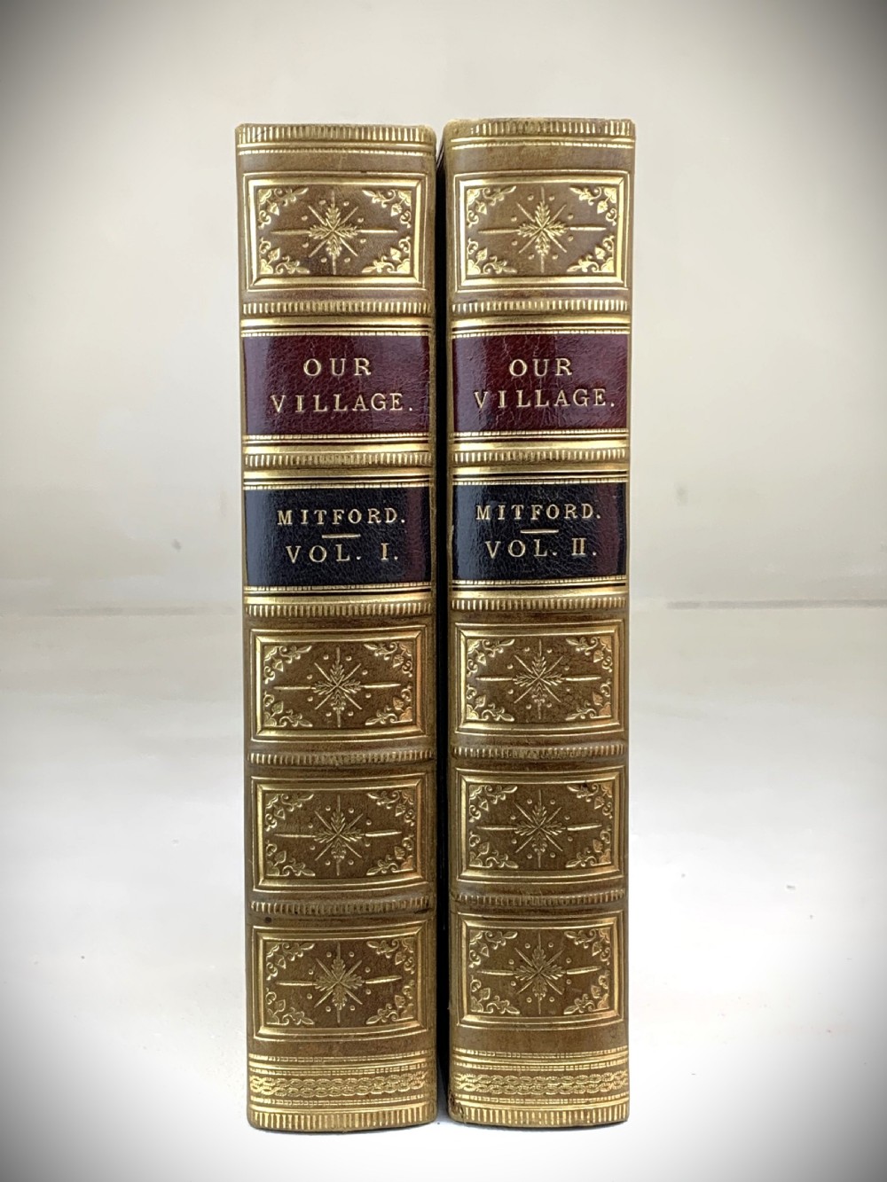 A two-volume set of 1848 leather-bound books titled Our Village, featuring elaborate gold tooling and raised spine bands. View II