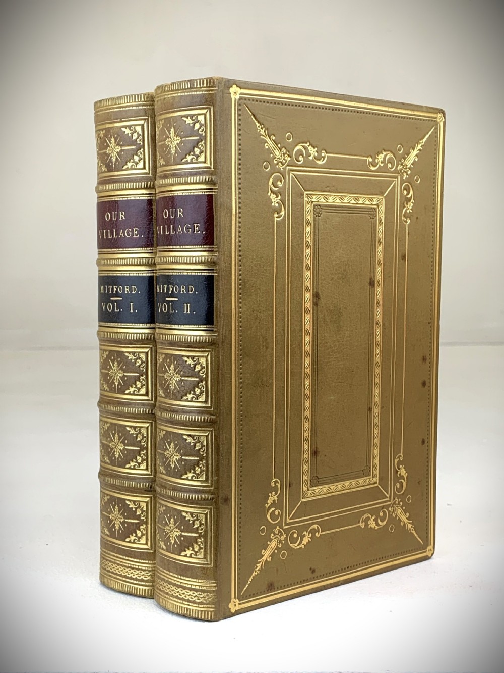 A two-volume set of 1848 leather-bound books titled Our Village, featuring elaborate gold tooling and raised spine bands. View III