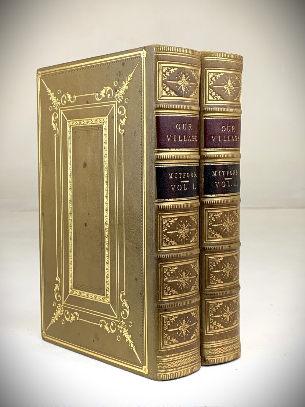 A two-volume set of 1848 leather-bound books titled Our Village, featuring elaborate gold tooling and raised spine bands. View X