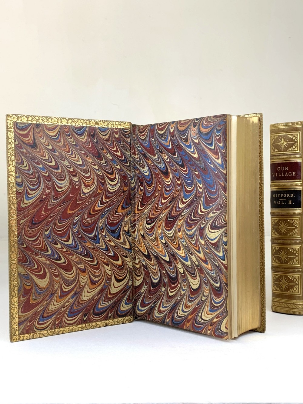 A two-volume set of 1848 leather-bound books titled Our Village, featuring elaborate gold tooling and raised spine bands. View XIV