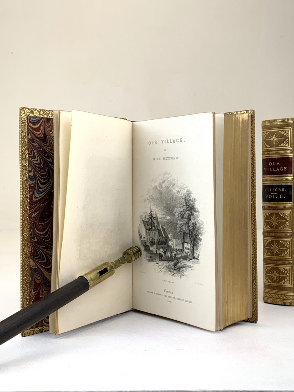 A two-volume set of 1848 leather-bound books titled Our Village, featuring elaborate gold tooling and raised spine bands. View XVI