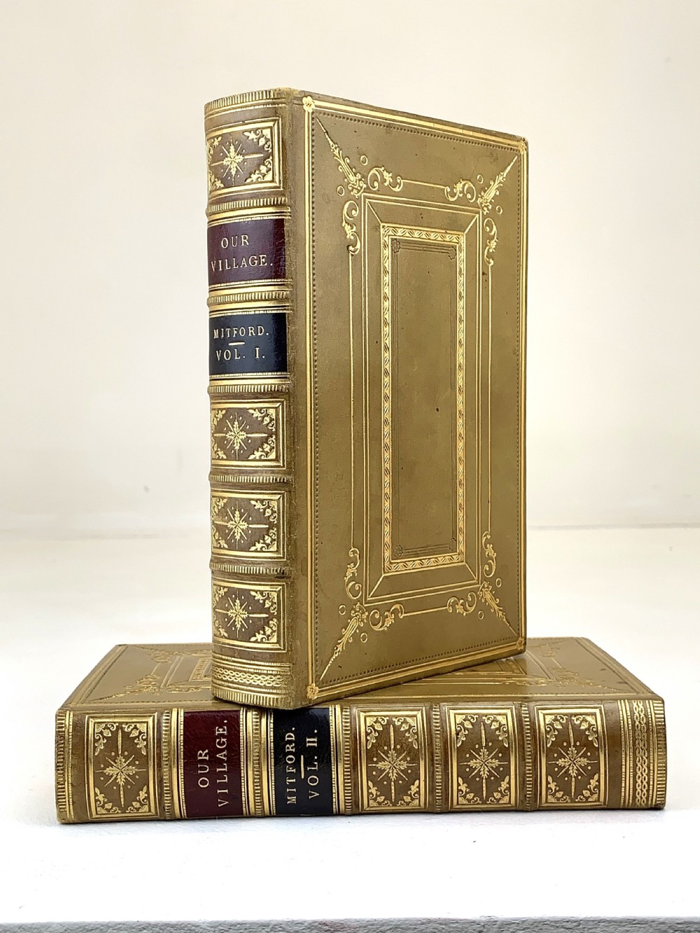 A two-volume set of 1848 leather-bound books titled Our Village, featuring elaborate gold tooling and raised spine bands. View XIX