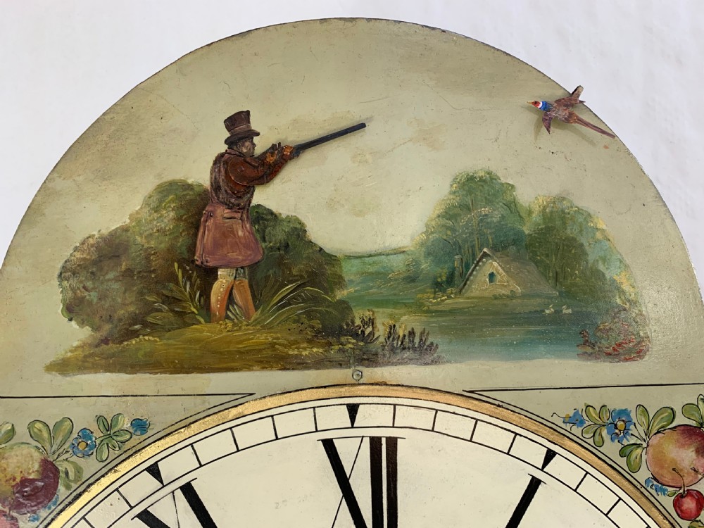 An antique Georgian flame mahogany longcase clock featuring three brass ball finials, an arched hood, and a hand-painted dial with Roman numerals. View III