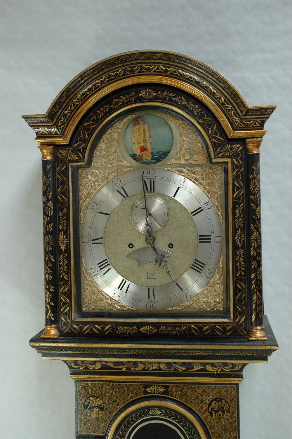 An 18th-century black lacquered longcase clock featuring gold chinoiserie landscape paintings, an arched hood, and a brass dial. View II