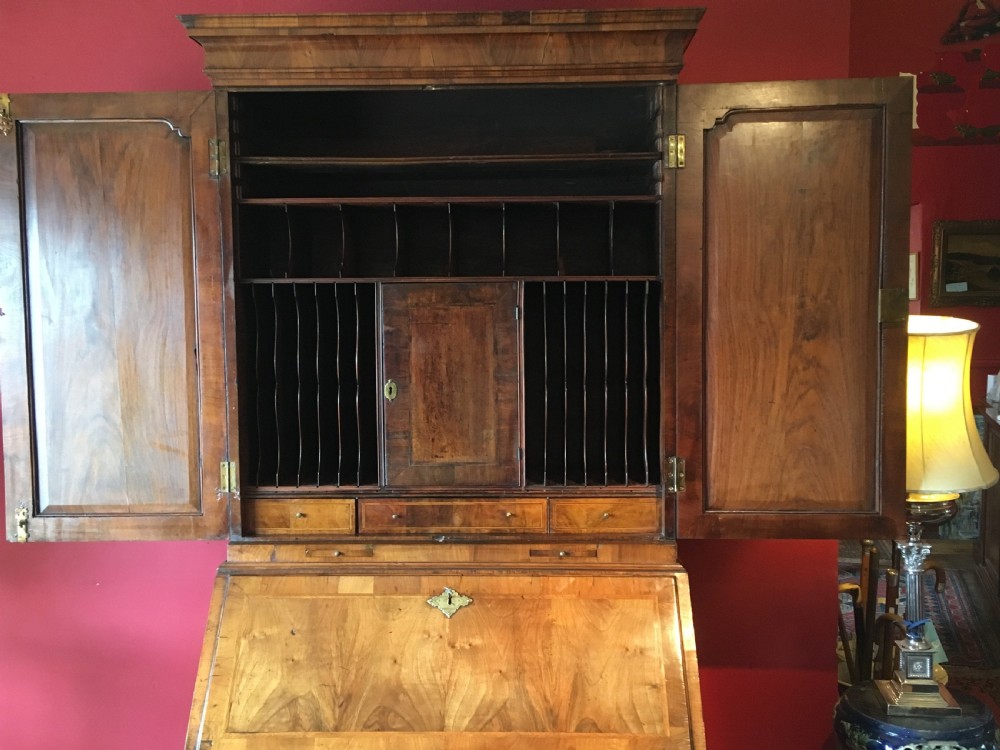 An early 18th-century Queen Anne walnut bureau bookcase featuring upper double mirrored doors, a fall-front writing desk with a fitted interior, and drawers below. View III