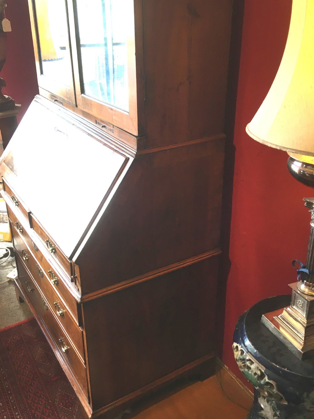 An early 18th-century Queen Anne walnut bureau bookcase featuring upper double mirrored doors, a fall-front writing desk with a fitted interior, and drawers below. View IV