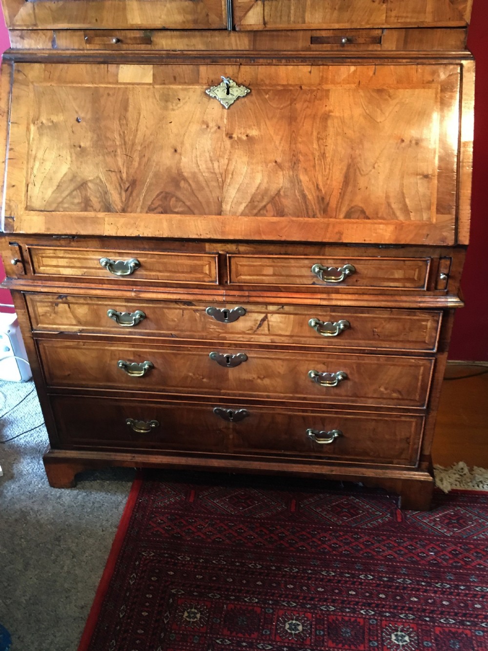 An early 18th-century Queen Anne walnut bureau bookcase featuring upper double mirrored doors, a fall-front writing desk with a fitted interior, and drawers below. View V