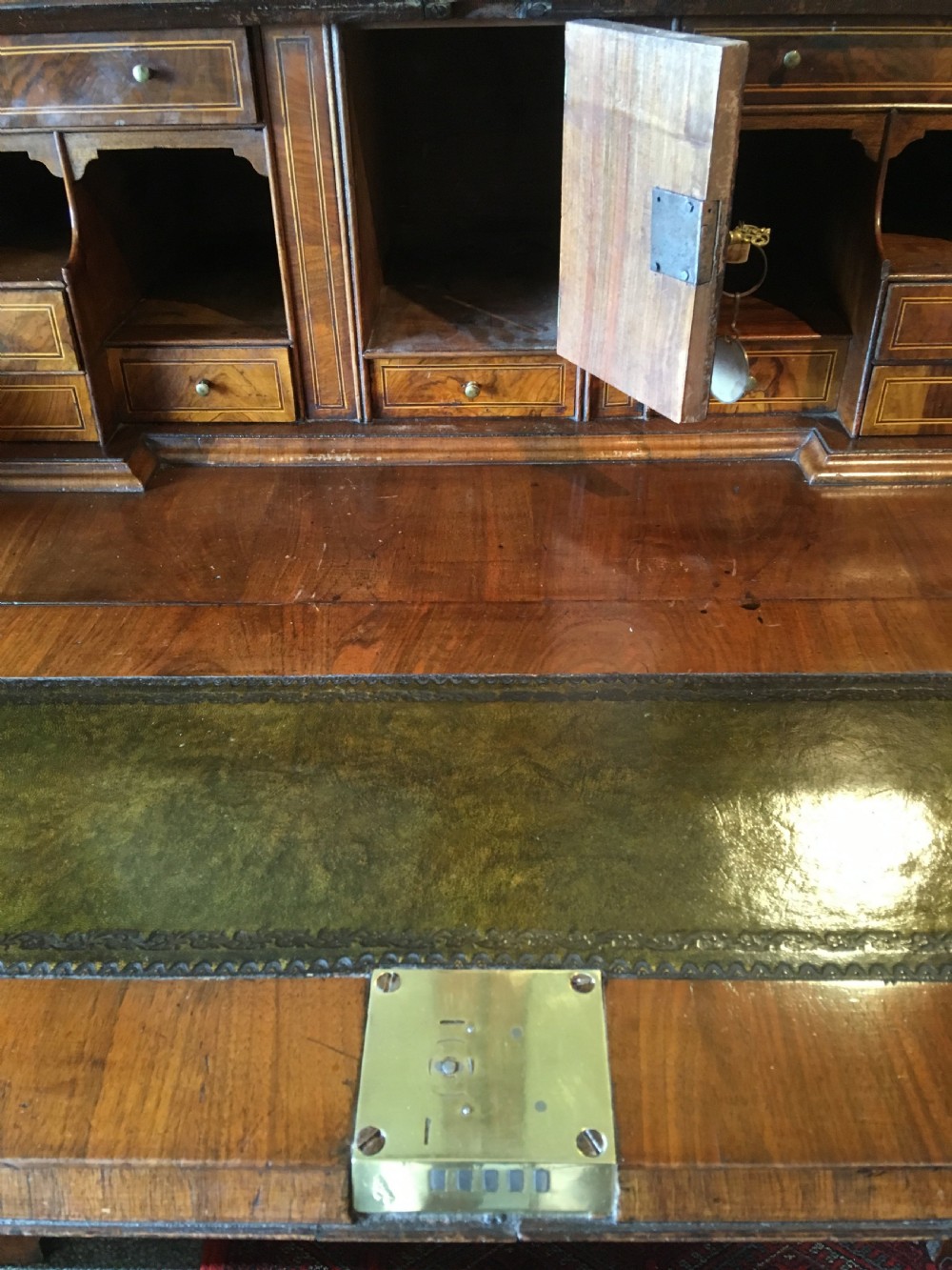 An early 18th-century Queen Anne walnut bureau bookcase featuring upper double mirrored doors, a fall-front writing desk with a fitted interior, and drawers below. View VI