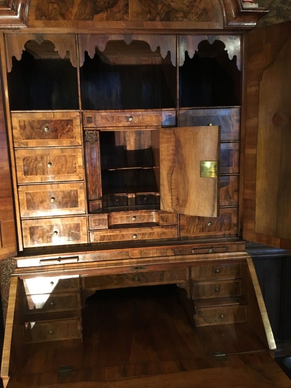 A George I walnut bureau bookcase featuring an arched pediment, two mirrored doors on the upper cabinet, and a sloping fall-front desk over three long drawers. View IV